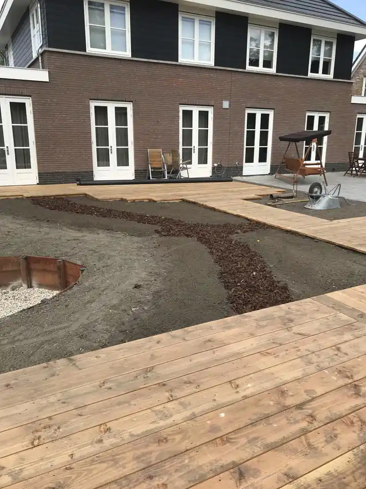 Uitgezette plantvakken en slingerende schorspaden in het zand naast de nieuwe vlonder, met een cortenstalen rand rond een aan te leggen vak