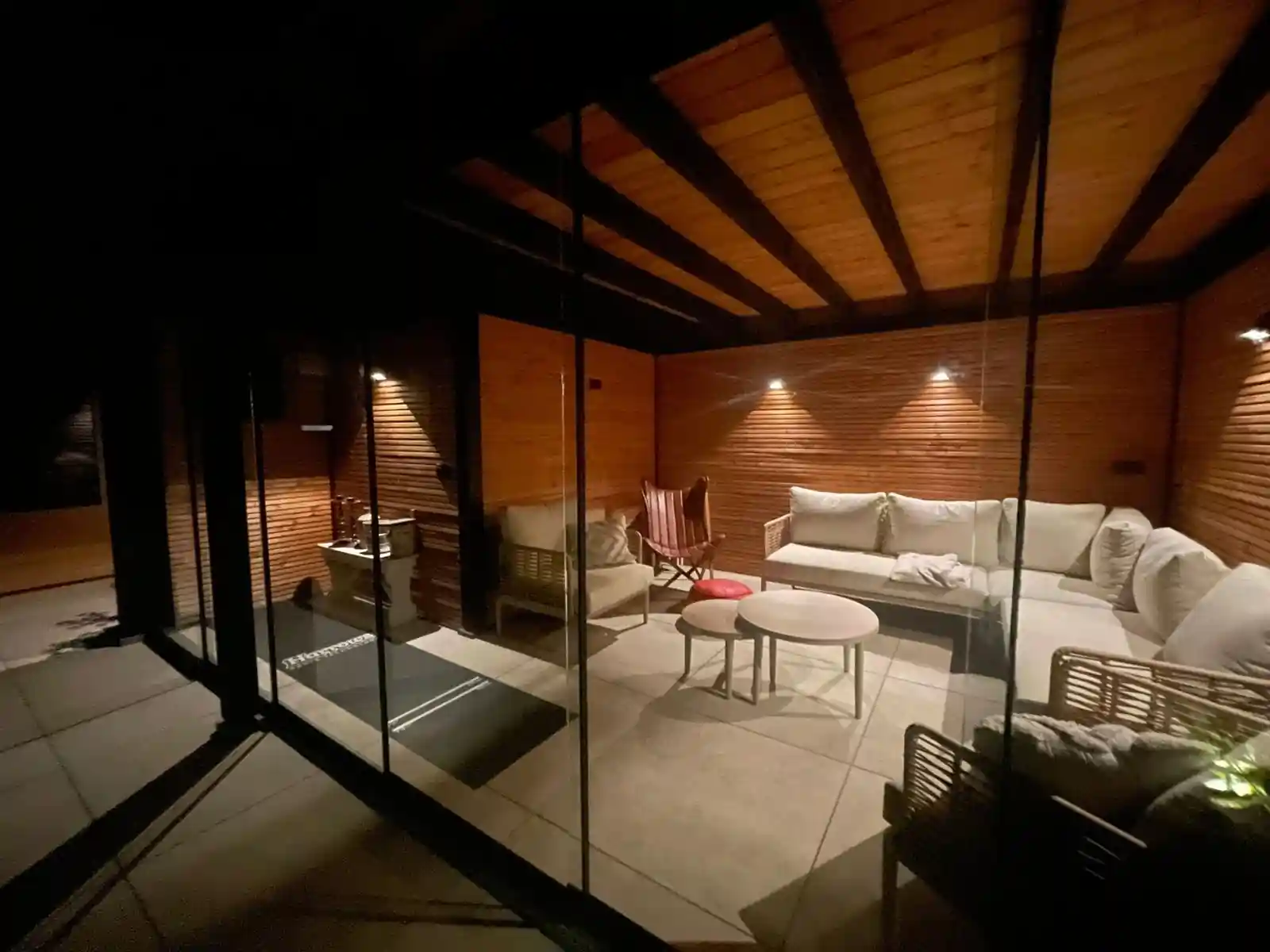 Interieur van de verlichte tuinkamer met lichte hoekbank, ronde salontafels en een Douglas plafond met zwarte balken